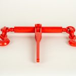 Ratchet load binder tightening a chain on a flatbed trailer, used for securing heavy equipment or cargo during transport.