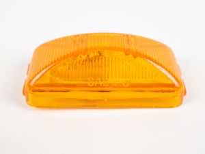 Amber plastic vehicle marker light cover stamped with "SAE PC" against a white background
