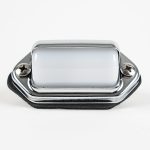 Front-angled view of a surface-mount chrome-hooded license plate light featuring a high-polish finish, two Phillips mounting screws, black foam mounting gasket, and wiring leads against a white background.