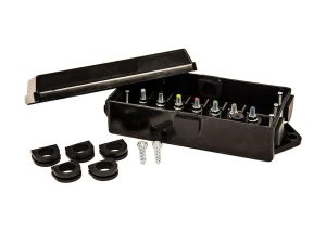 Black plastic trailer junction box with the lid open, displaying color-coded terminal studs alongside rubber grommets and mounting screws.